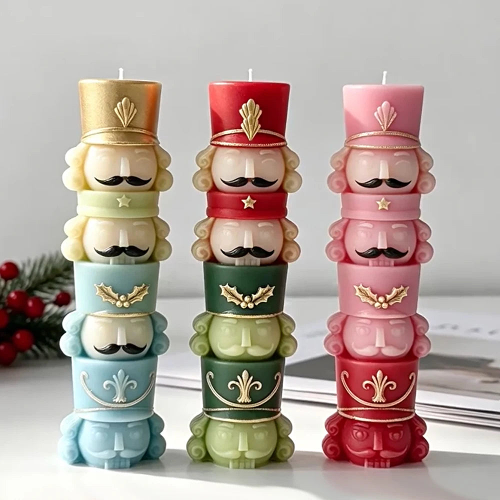 Three finished stacked nutcracker soldier candles in cream, red and pink, each with four figures and decorated tall hats