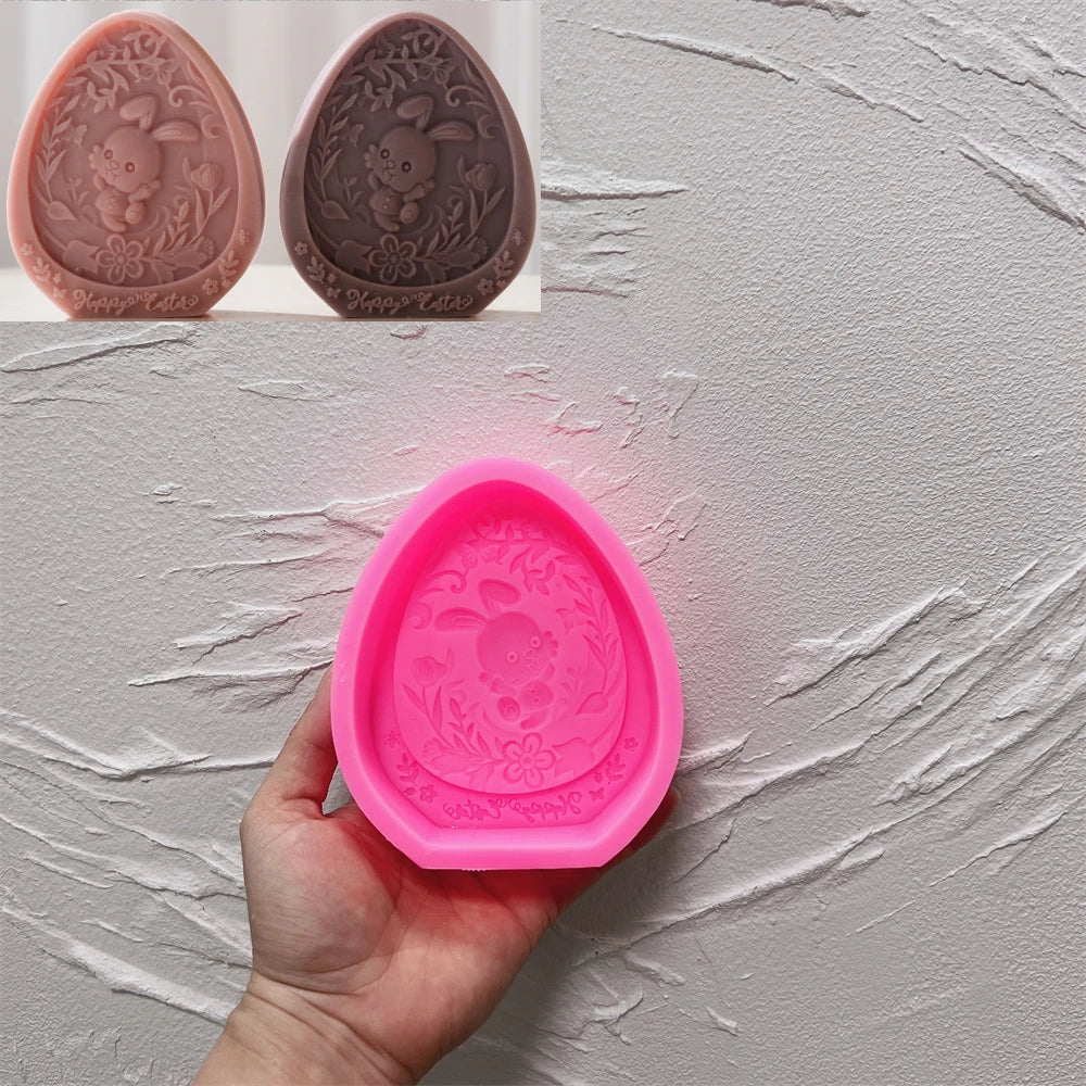 Pink silicone mold shaped like an egg with a design, held by a hand against a gray textured background.