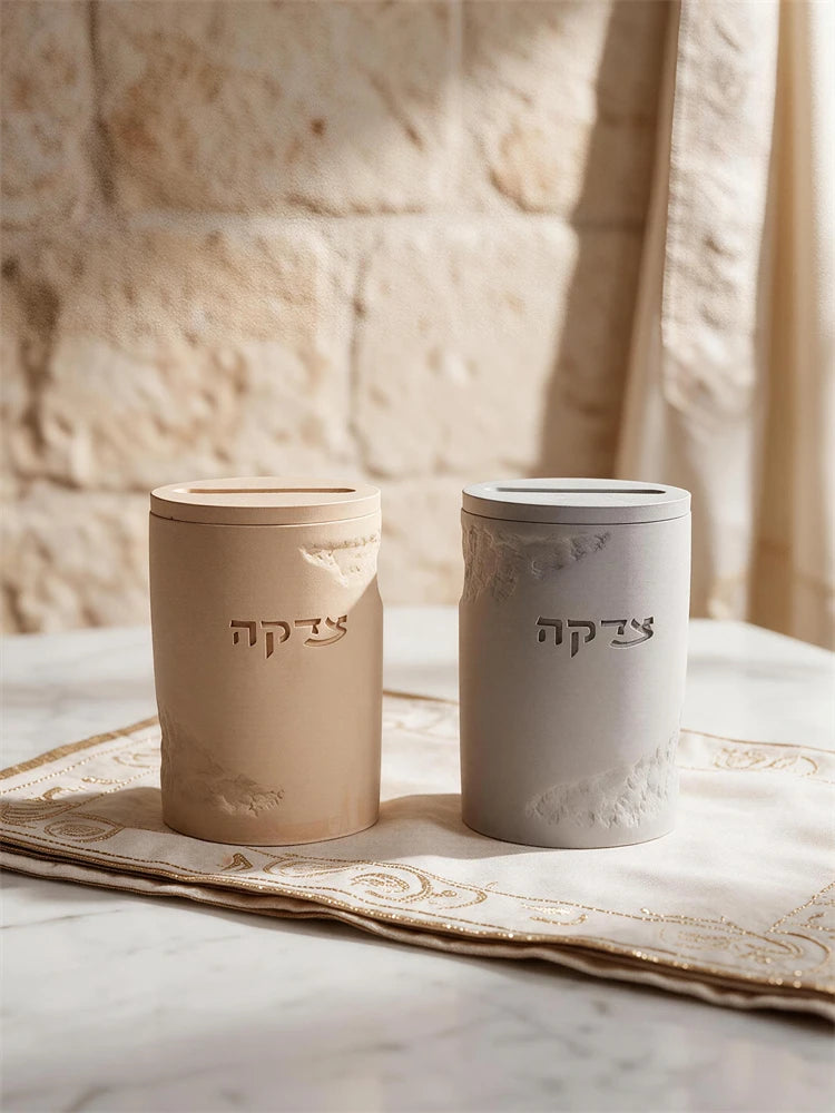 Two cylindrical Tzedakah charity boxes with Hebrew lettering and coin-slot tops
