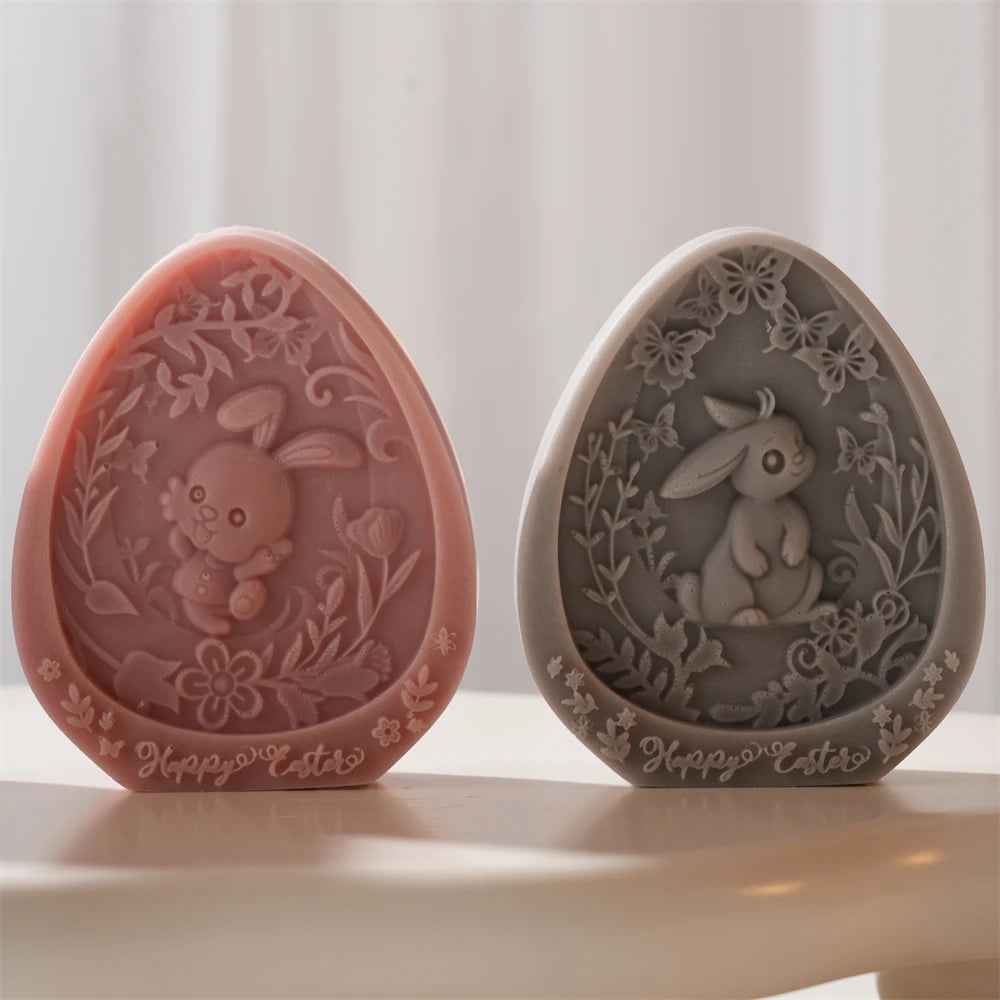 Two decorative egg-shaped molds with rabbit designs on a white surface.
