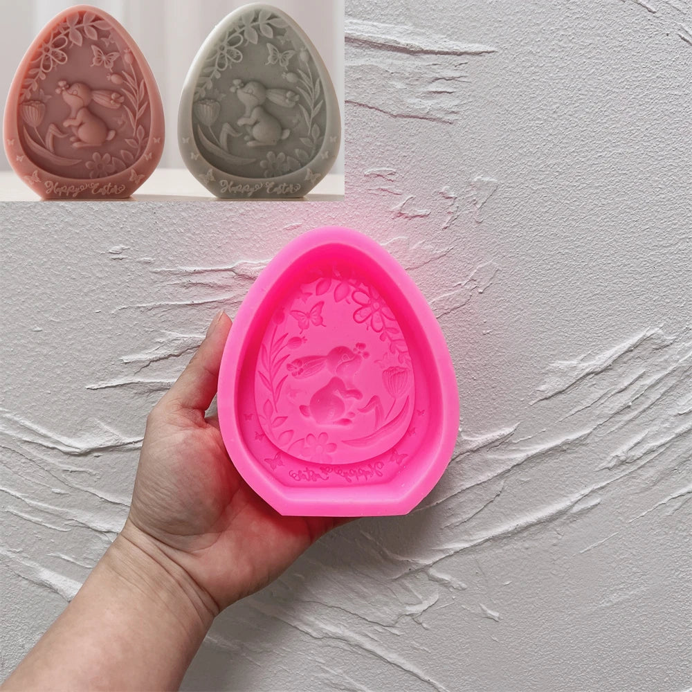 Pink silicone mold with decorative design held by a hand against a textured gray background.