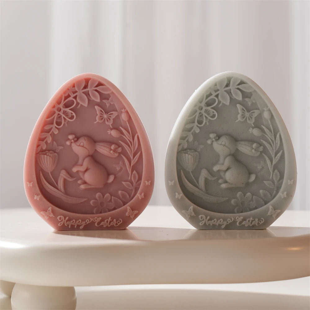 Two decorative Easter eggs with rabbit and floral designs on a white surface.