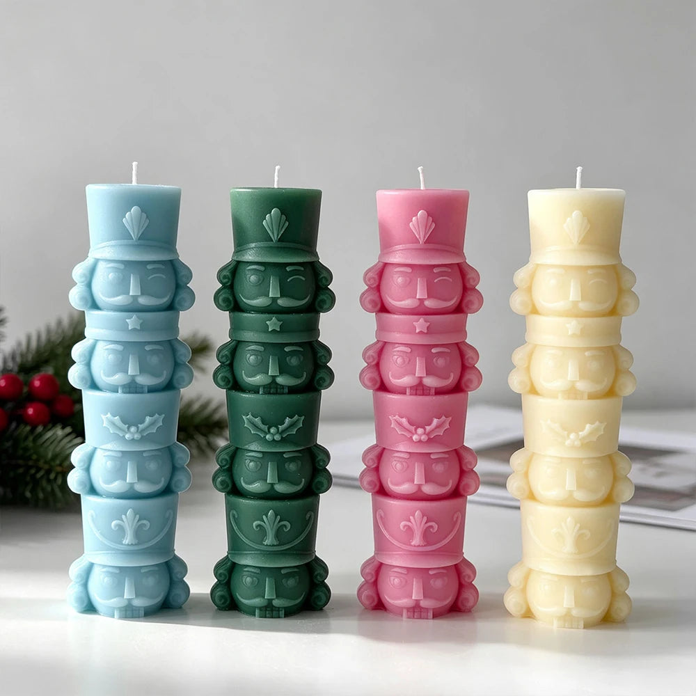 Four solid-colour stacked nutcracker candles in light blue, green, pink and cream showing the repeated soldier design